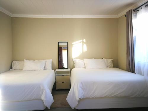 two beds in a hotel room with white sheets at Sunrise On Sea Backpackers in Port St Johns