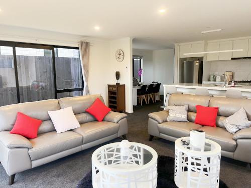 a living room with two couches and a kitchen at 7th Heaven on Waikato River in Hamilton