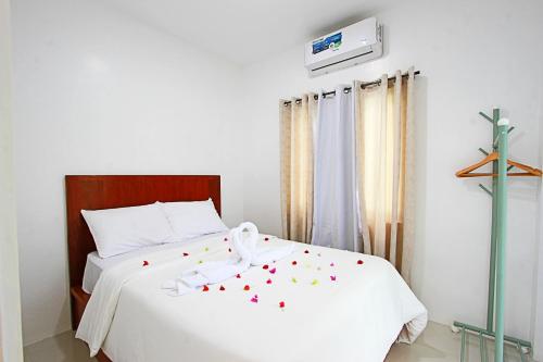 a bedroom with a white bed with a cross on the wall at the Landing Villas rental in Panglao