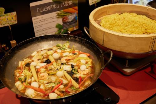 a pan of food on a stove with a bowl of rice at Almont Hotel Sendai in Sendai