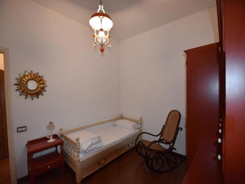 a bedroom with a bed and a chair and a chandelier at Villa in Valdora with Lake Maggiore Views in Ghiffa