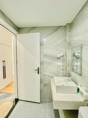 a white bathroom with a sink and a mirror at Happy Nest Home - Long Bien in Hanoi