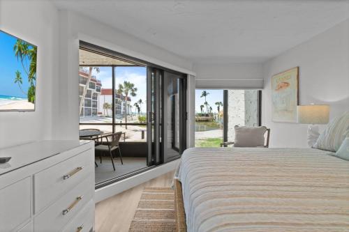 a white bedroom with a bed and a view of a patio at Pointe Santo C1 in Sanibel