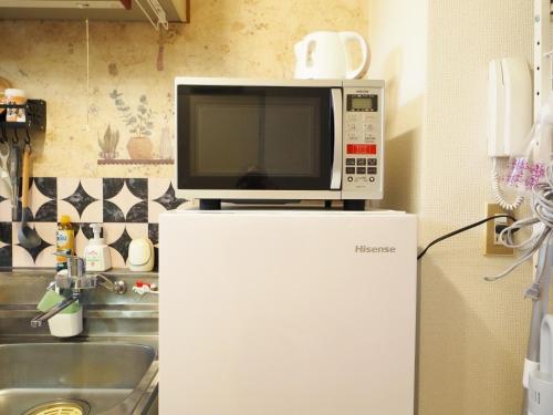 a microwave on top of a refrigerator in a kitchen at 203 Near Koiwa st Airport Disney Direct Bus Max3人 in Tokyo