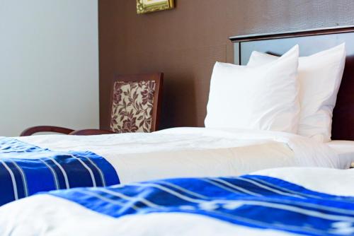 two beds in a hotel room with white and blue sheets at Best Western Okinawa Kouki Beach in Nago