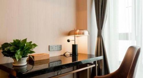 a desk with a lamp and a plant on it at James Joyce Coffetel Harbin West High-speed Railway Station Wanda Plaza in Harbin