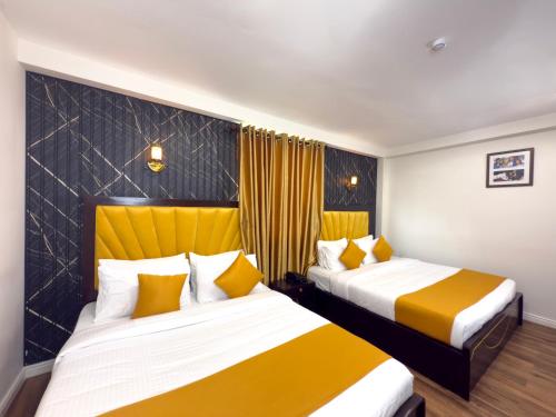 two beds in a hotel room with yellow and white at London Eye Hotel Nuwaraeliya in Nuwara Eliya