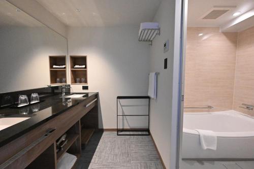 a bathroom with a large tub and a sink at Best Western Okinawa Kouki Beach in Nago