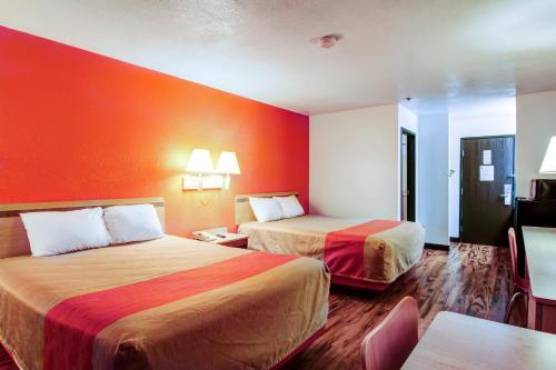 a hotel room with two beds with orange walls at Motel 6-Columbia, MO - East in Columbia