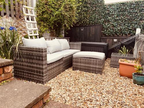 a patio with a couch and a bench in a garden at Spacious 5 Bedroom Home in Central Kidderminster with Private Parking and Electric Vehicle Facilities, Easy Access to Birmingham and Nearby Towns in Kidderminster
