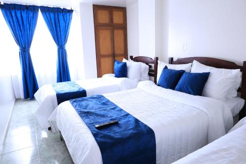 two beds in a hotel room with blue curtains at Hotel San Lorenzo Ubaté in Ubaté