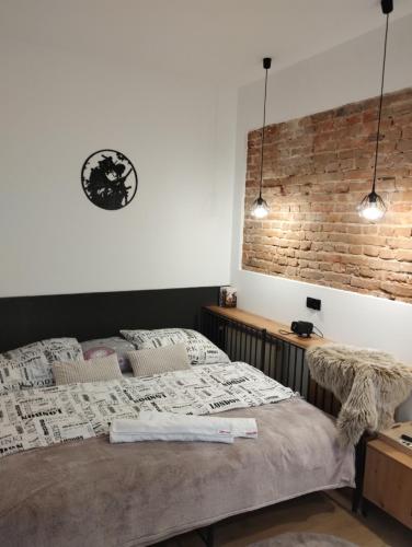 a bedroom with a bed and a brick wall at Apartment romantyczny SAKURA in Jędrzejów