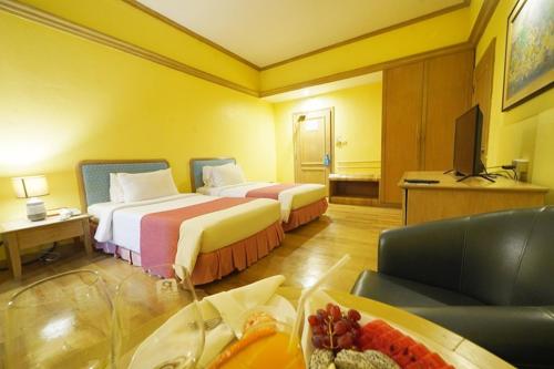 a hotel room with two beds and a television at Riverside Bangkok Hotel in Bangkok