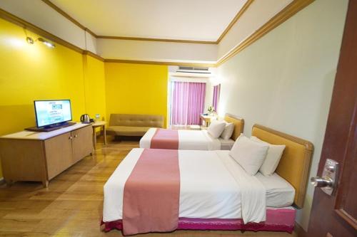 a hotel room with two beds and a desk at Riverside Bangkok Hotel in Bangkok