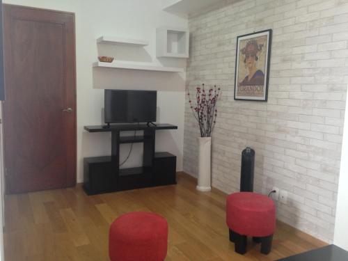 a living room with two red chairs and a television at Beautiful, down-town in Mexico City