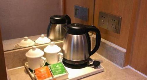 a tea kettle and cups on a kitchen counter at Vienna Hotel Guangdong Zhaoqing Sihui Tianguangxu in Zhaoqing