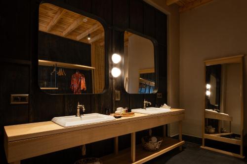 a bathroom with two sinks and two mirrors at The Postcard in The Himalayan Willows, Stok, Leh in Leh
