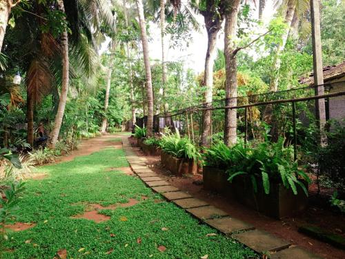 a path in a garden with palm trees and a fence at Happy Three Holiday Homes in Hikkaduwa