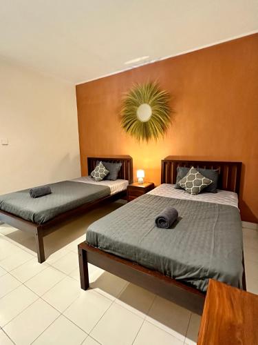 a bedroom with two beds and a plant on the wall at Simon Homestay in Sanur