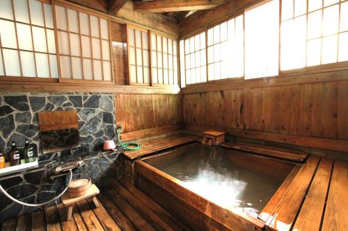 a large bath tub in a wooden room with windows at ひらゆの森別邸湯う香三蔵庵 in Takayama