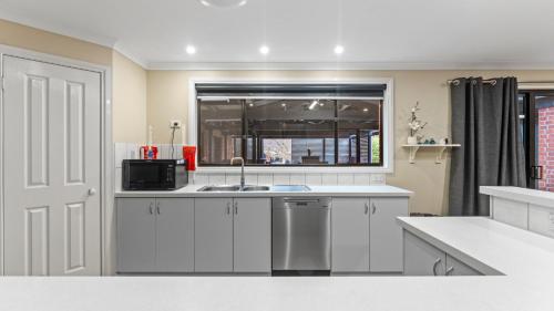 a kitchen with white cabinets and a sink and a window at McDougall Hidaway in Magpie