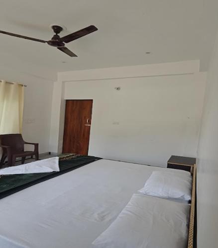 a bedroom with a white bed with a ceiling fan at CSR Palace Langasu By StayApart in Karnaprayāg