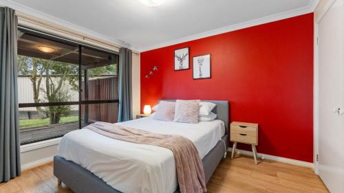 a red bedroom with a bed and a window at McDougall Hidaway in Magpie