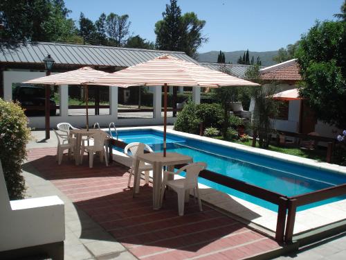 un patio con tavoli e ombrelloni accanto alla piscina di El Agora a Villa General Belgrano