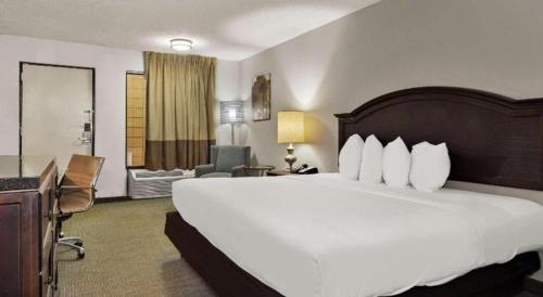 a hotel room with a large white bed and a chair at Rodeway Inn Lumberton Central in Lumberton