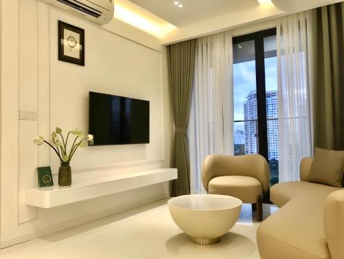 a living room with a tv and a couch and a chair at Lumiere Riverside Heera Stay Apartment in Ho Chi Minh City