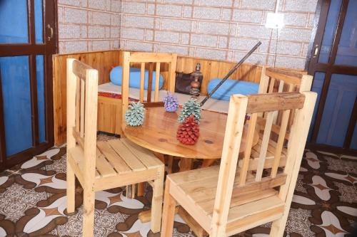 a wooden table and two chairs and a table and a room at Bhaskar Villa in Sainj