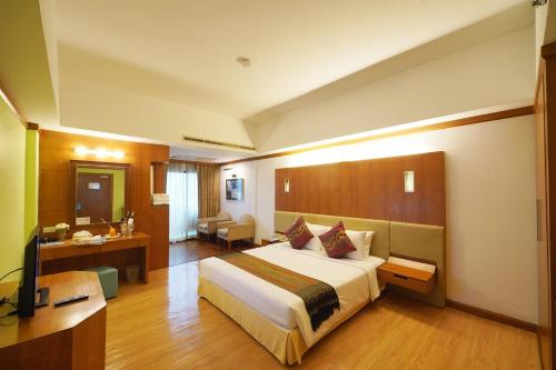 a hotel room with a large bed and a desk at Riverside Bangkok Hotel in Bangkok