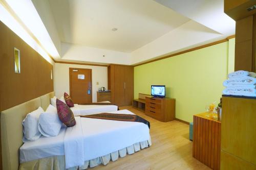 a hotel room with two beds and a television at Riverside Bangkok Hotel in Bangkok