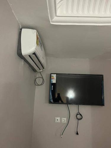 a mirror on a wall with a tv and a hair dryer at Hotel Le Bachelor in Yaoundé