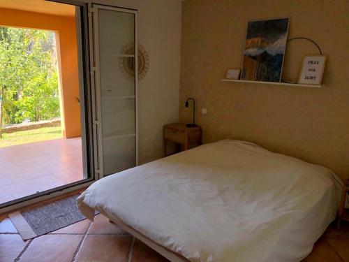 une chambre avec un lit et une porte coulissante en verre dans l'établissement Les Palmiers - Saint Florent, à Saint-Florent