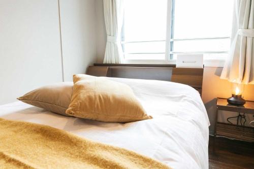 a white bed with a pillow and a window at Twinberry CHITOSE in Chitose