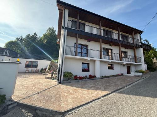 a large white building with a balcony and a patio at Pod Skałką in Sromowce Wyżne