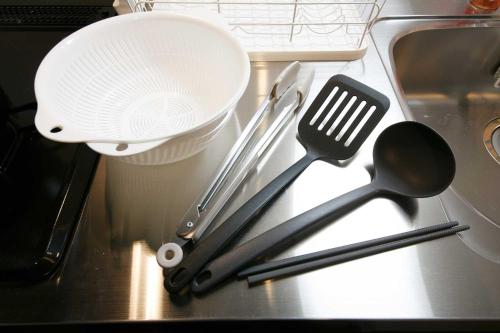 a pile of kitchen utensils on a counter next to a sink at Twinberry CHITOSE in Chitose
