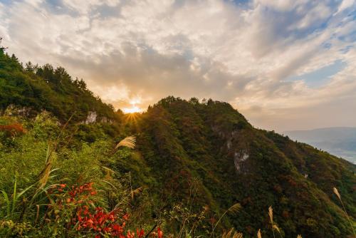 a view of a mountain with the sun setting on the horizon at Zhangjiajie Jijiehao Inn in Zhangjiajie