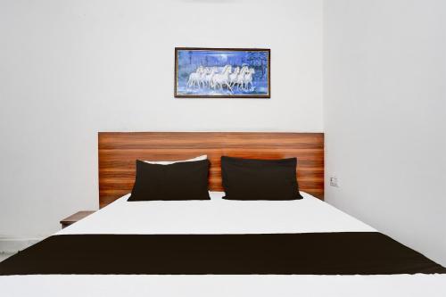 a bedroom with a white bed with a wooden headboard at Hotel O Mayur Deluxe in New Delhi