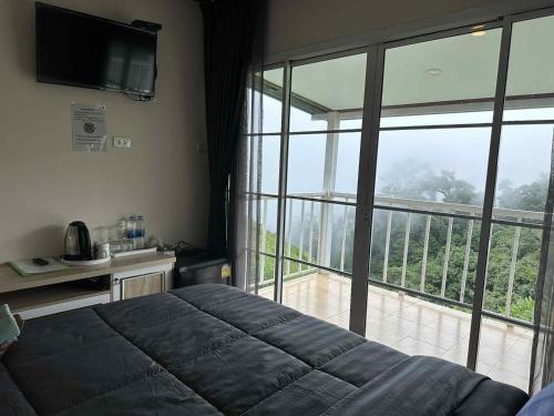 a bedroom with a bed and a large window at สเตชั่นภูทับเบิก-บ้านดาดฟ้าทะเลหมอก in Ban Tha Kok Hai