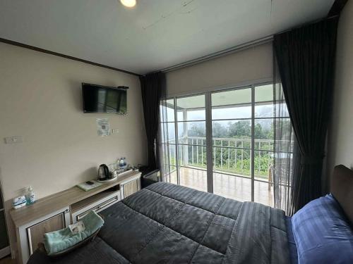 a bedroom with a bed and a large window at สเตชั่นภูทับเบิก-บ้านดาดฟ้าทะเลหมอก in Ban Tha Kok Hai