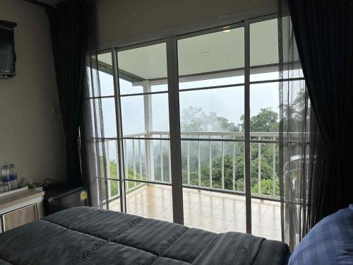 a bedroom with a large window looking out onto a patio at สเตชั่นภูทับเบิก-บ้านดาดฟ้าทะเลหมอก in Ban Tha Kok Hai