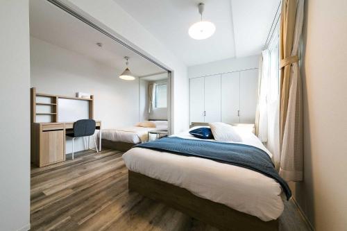 a bedroom with two beds and a desk in it at Twinberry CHITOSE in Chitose
