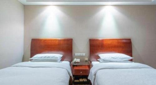 two beds in a hotel room with white sheets at Hohhot Hai Liang Plaza Hotel in Hohhot