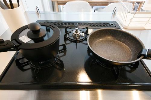 a stove with two pots and a pan on it at Twinberry CHITOSE in Chitose