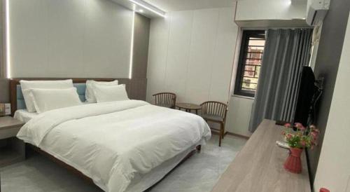 a bedroom with a large white bed and a window at Movie Star Hotel in Guangzhou