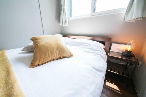a bedroom with a bed with a pillow and a window at Twinberry CHITOSE in Chitose