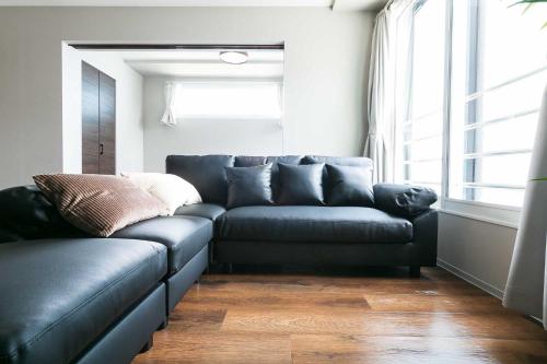 a living room with a leather couch and a window at Twinberry CHITOSE in Chitose