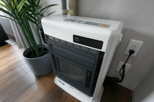 a white air conditioner sitting next to a potted plant at Twinberry CHITOSE in Chitose